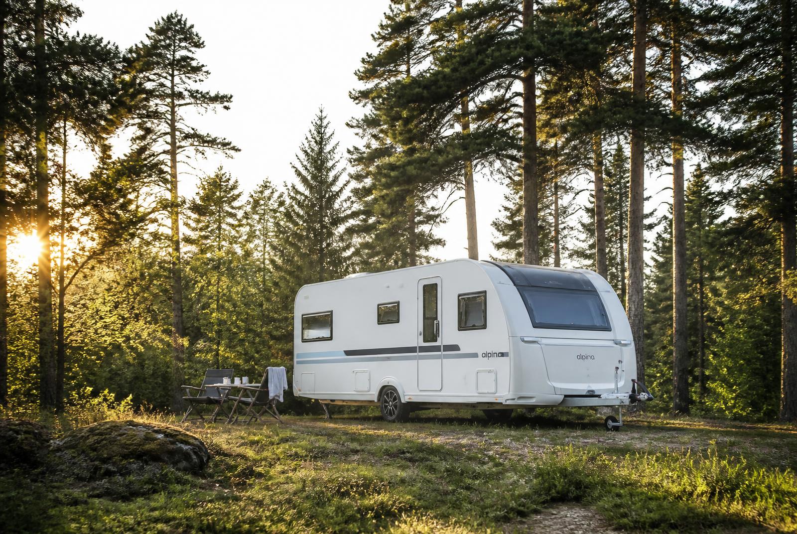A touring caravan pitched on a grassy site at golden hour